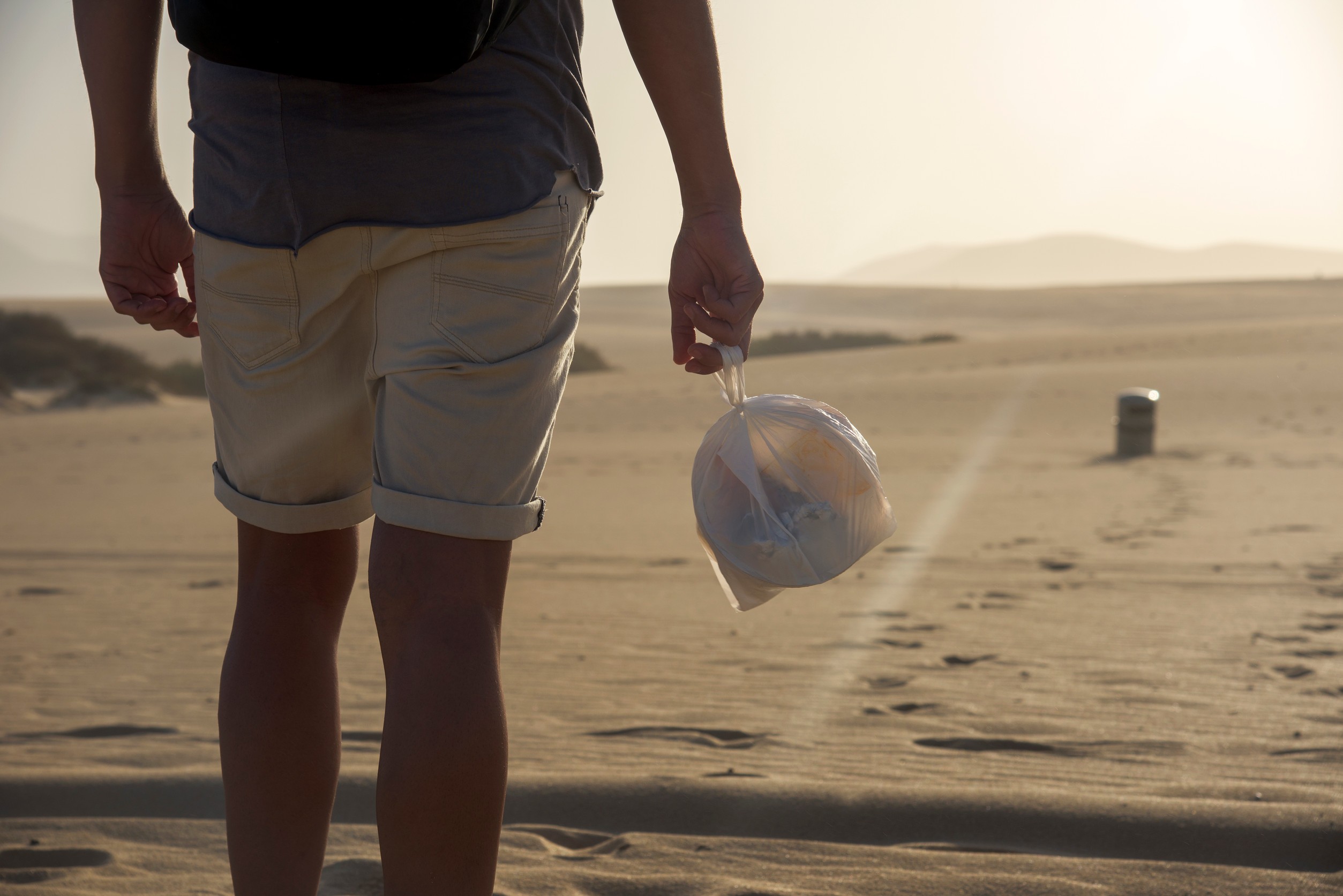 A Man Collecting Leftovers In A Bag As He Walks Ahead