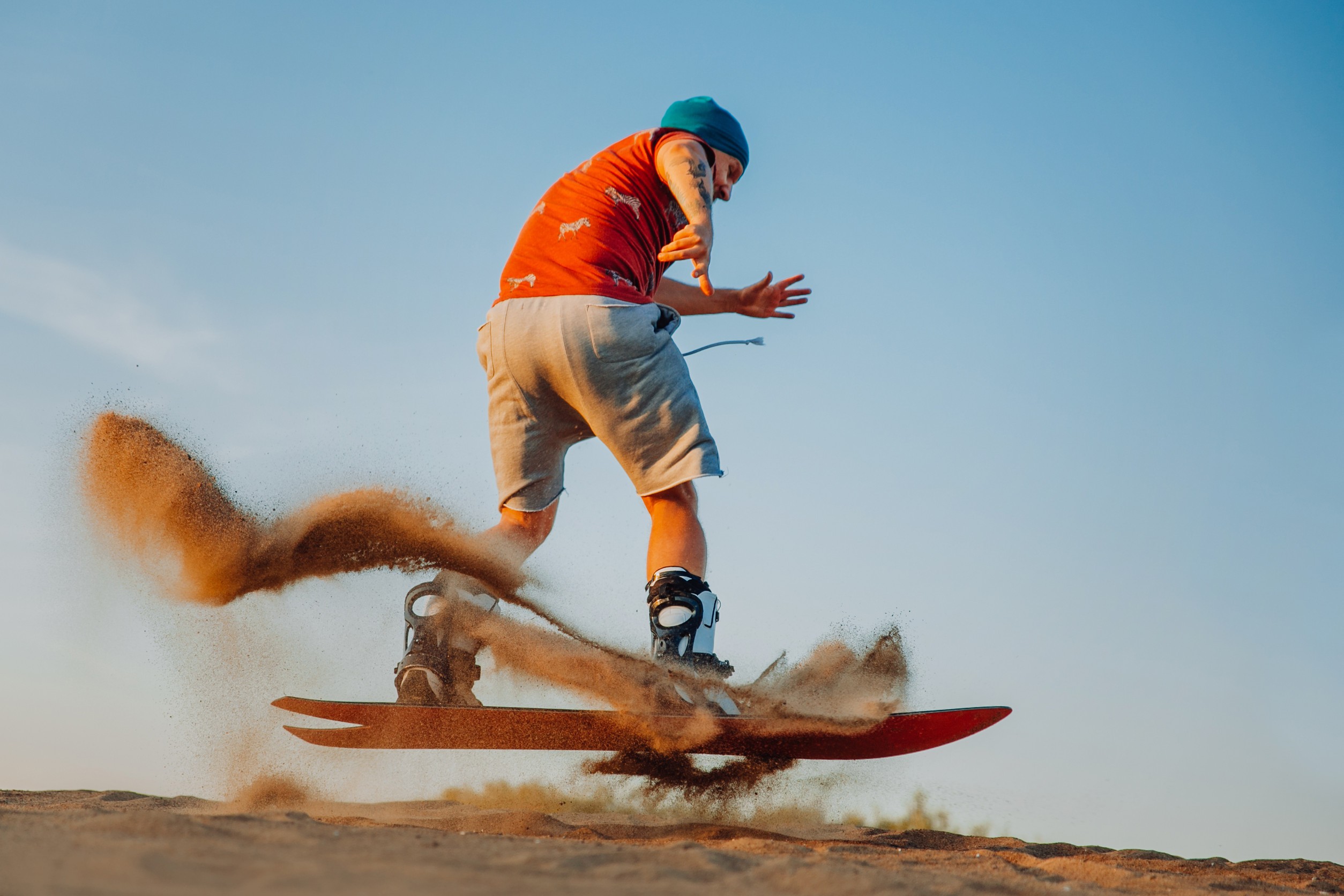 A Tourist Sandboarding In The Arabian Desert